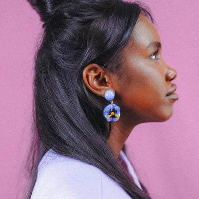 Femme portant des boucles d'oreilles Pensée couleur bleuet