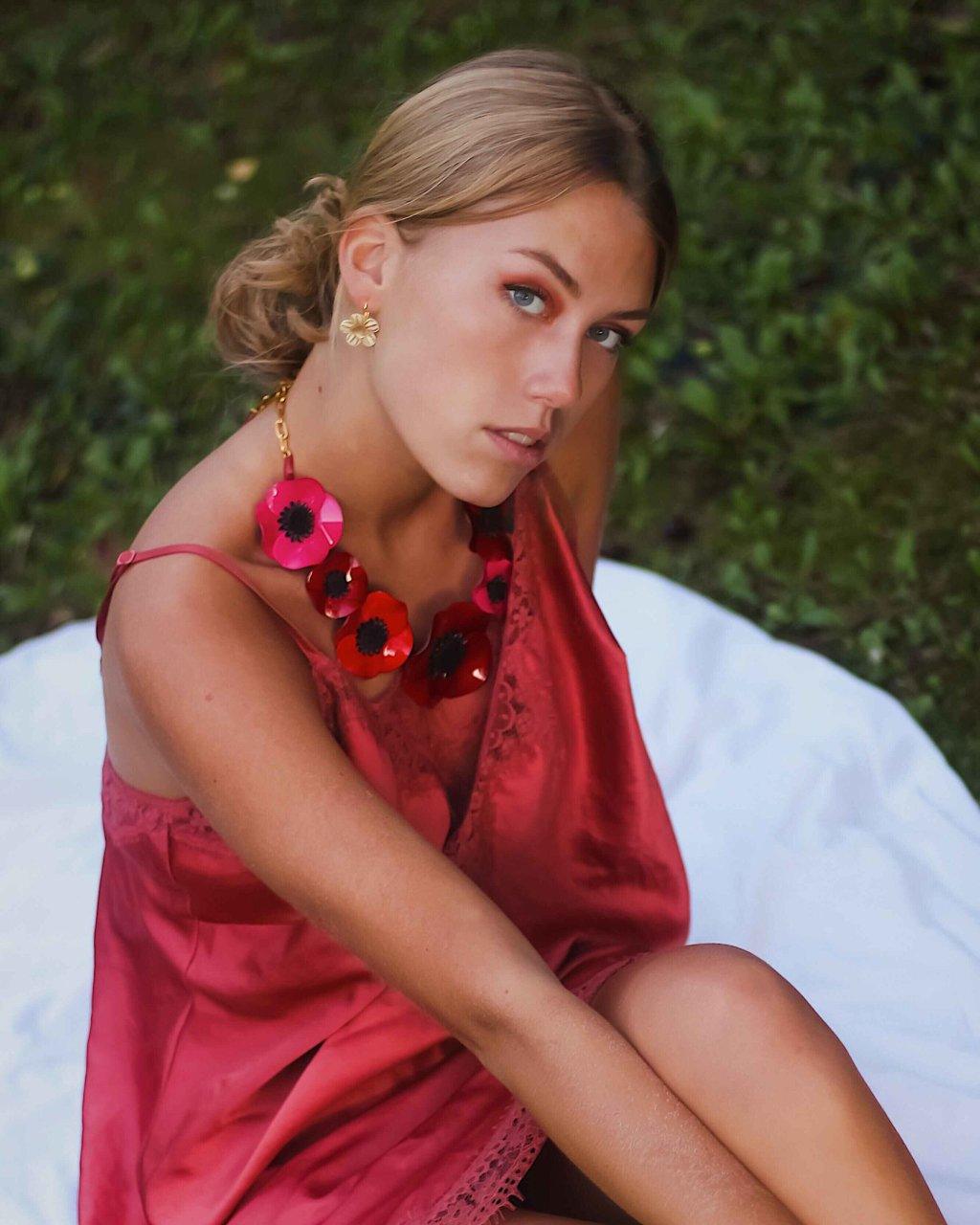 all-groups Femme portant un grand collier coloré femme aux fleurs rouges