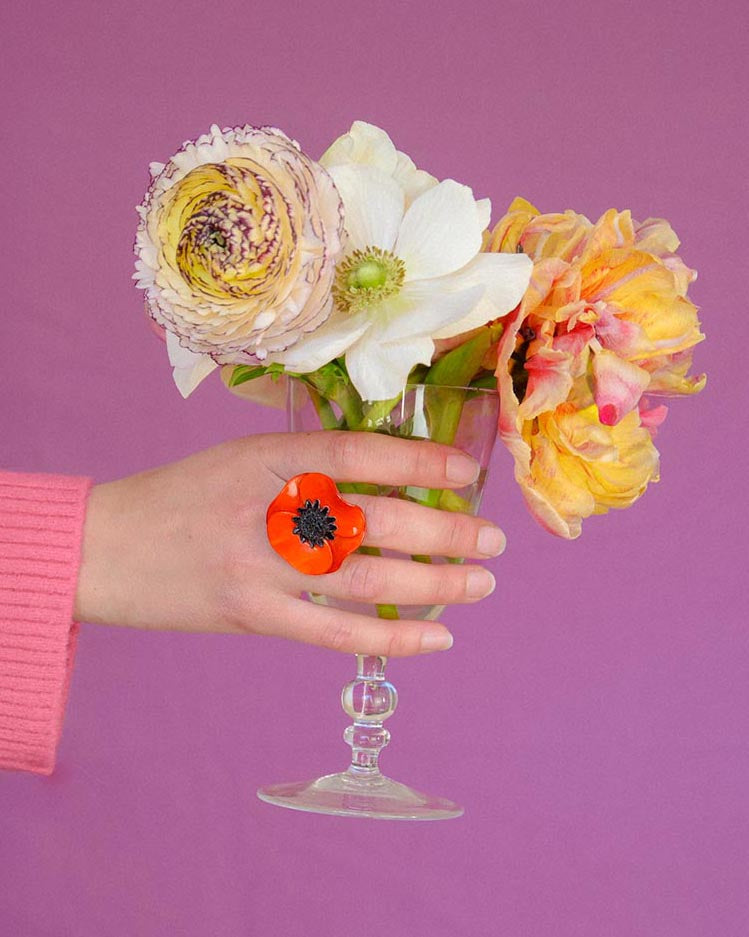 Main avec une bague fantaisie orange tenant des fleurs all-groups