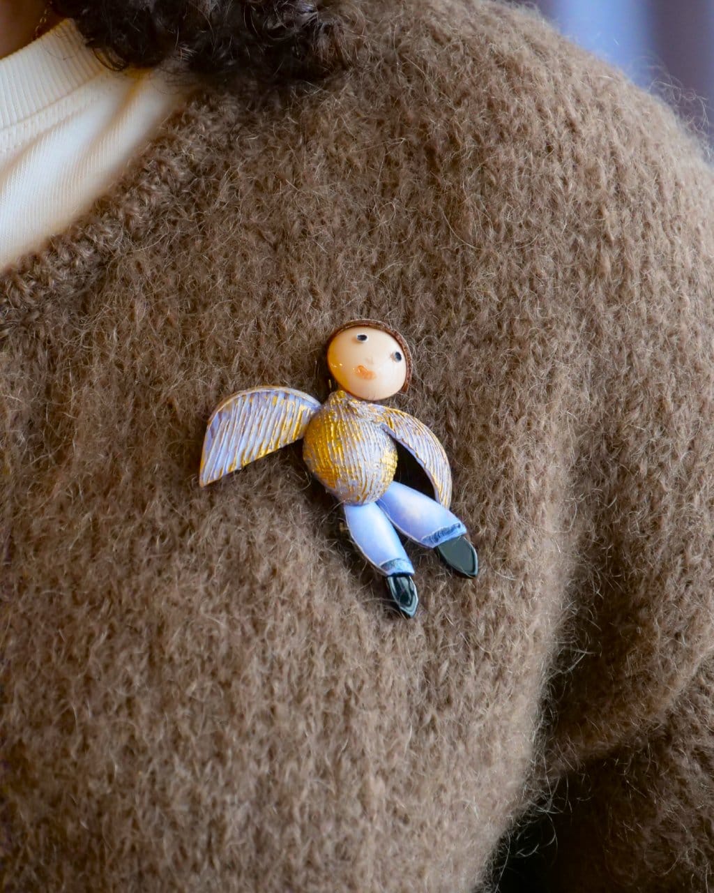 all-groups bijoux broche icare portée par une jeune femme avec un pull marron