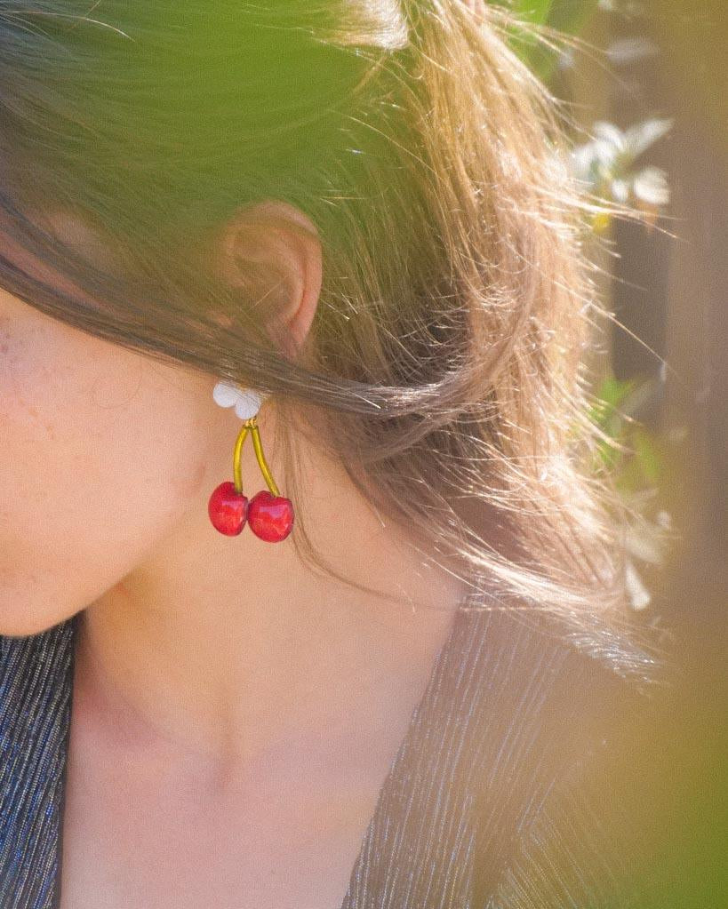 Femme portant des boucles d'oreilles cerises rouges