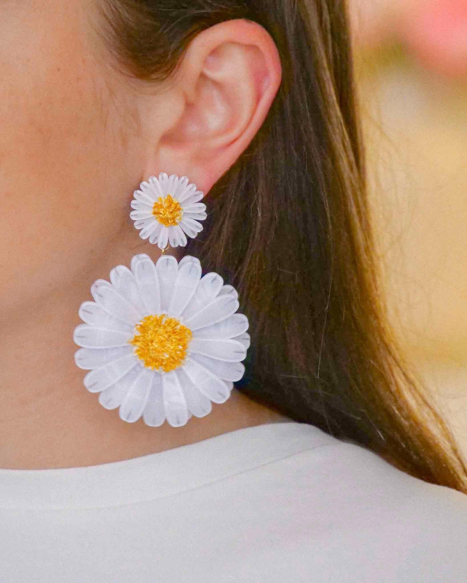 Femme portant une boucle d'oreille femme fantaisie marguerite