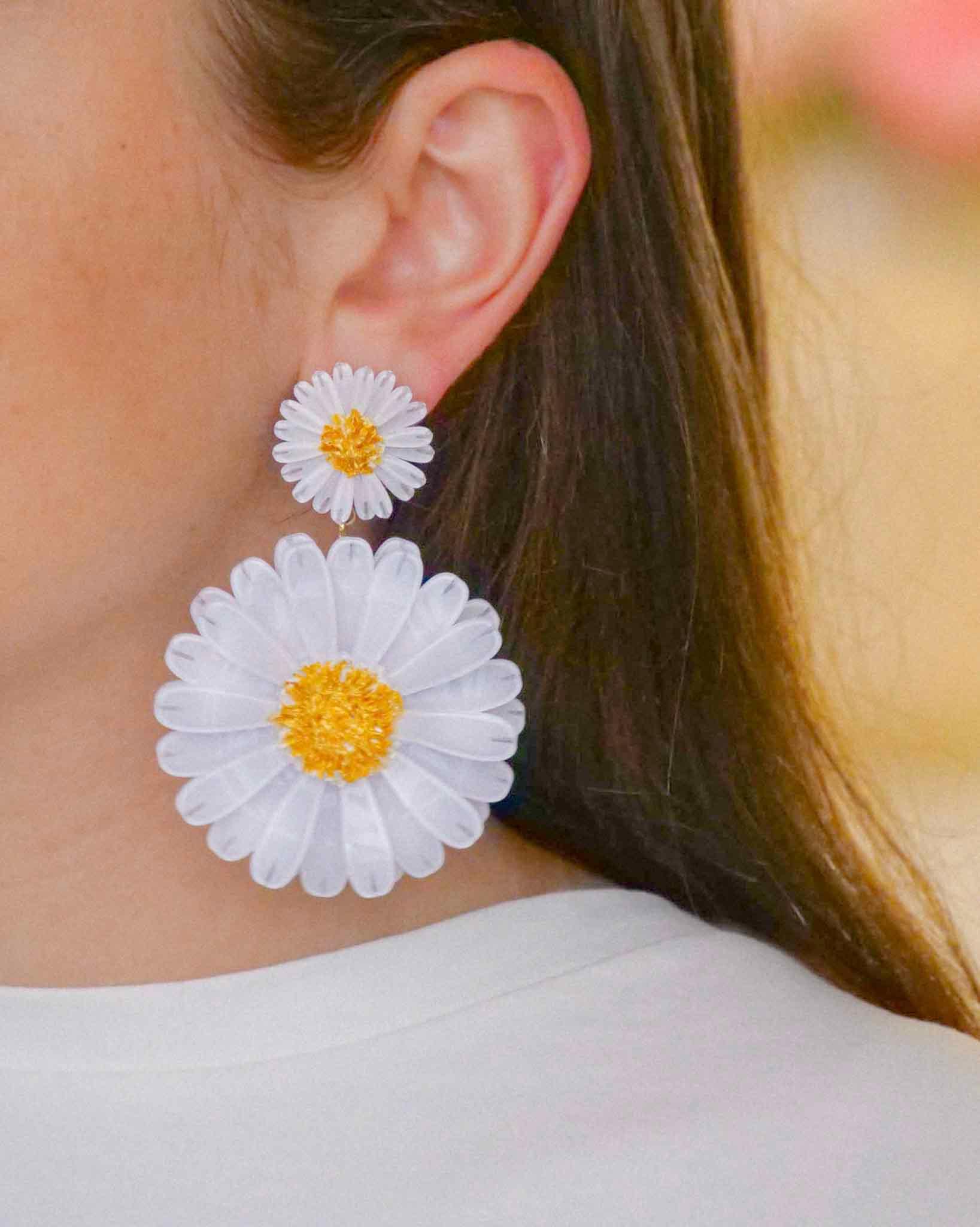 Femme portant une boucle d'oreille femme fantaisie marguerite