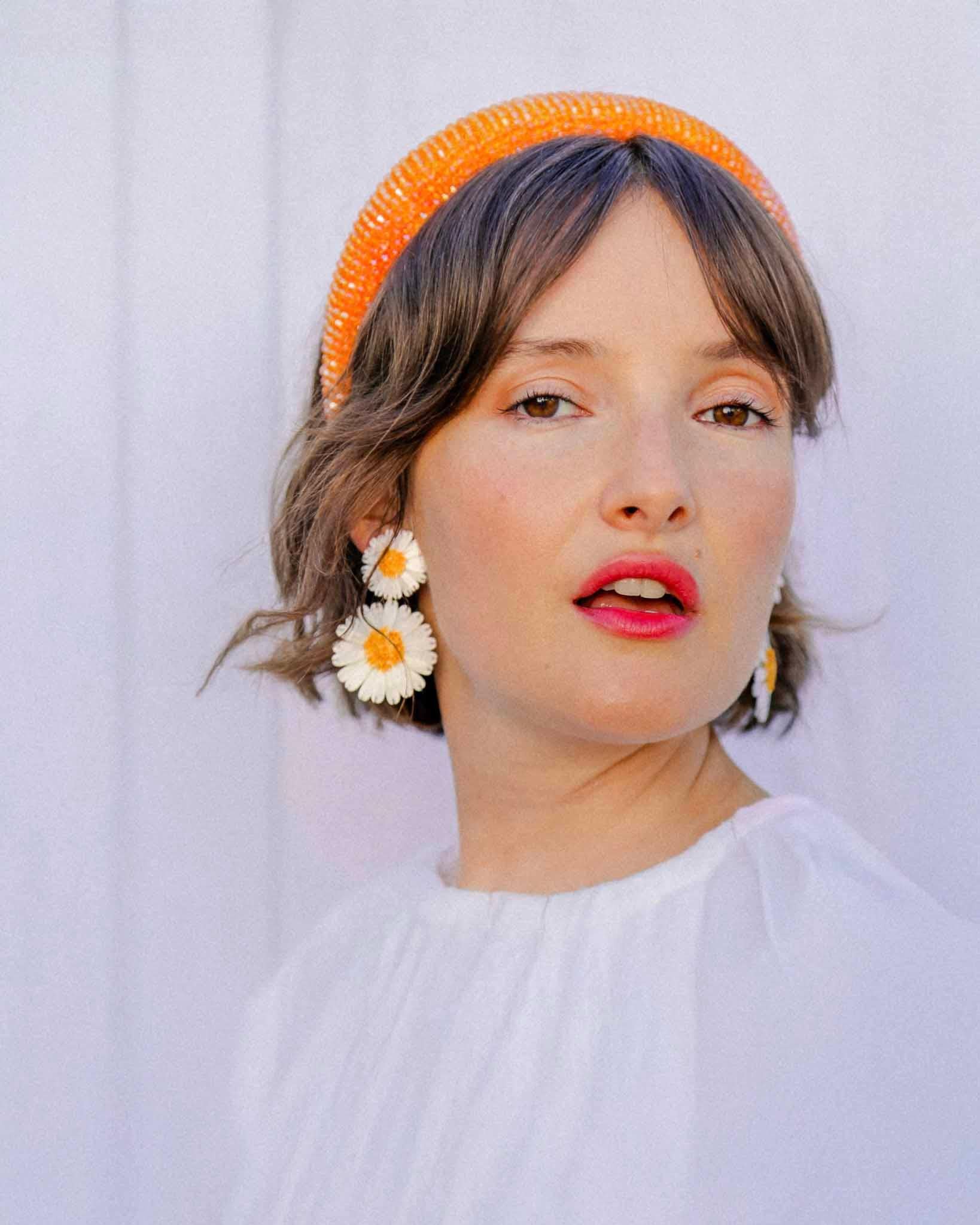 Femme portant une boucle d'oreille femme pendante marguerite