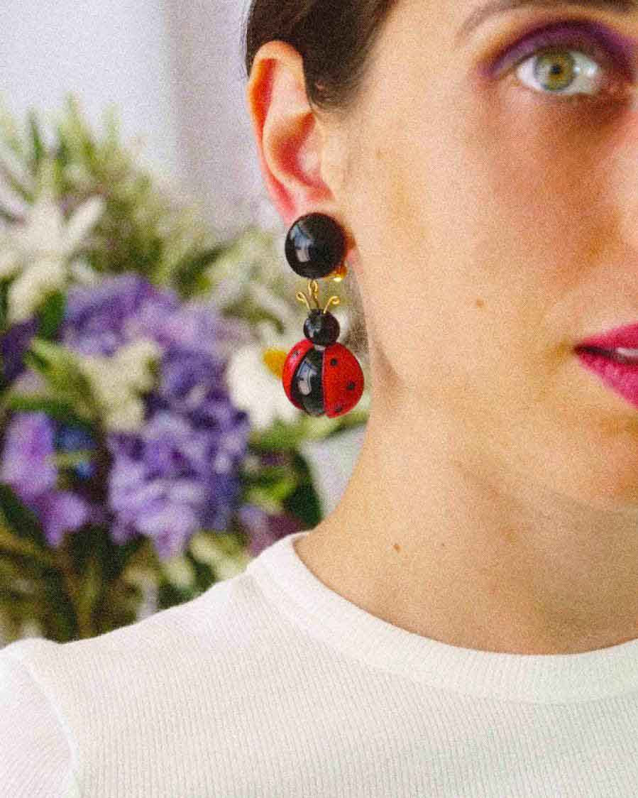 Femme portant des boucles d'oreilles coccinelles pendantes rouges et noires