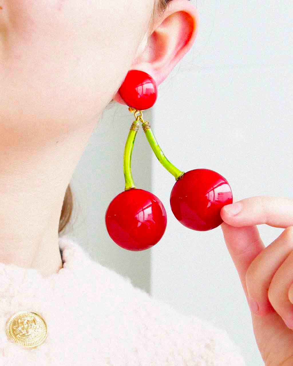 Femme portant une boucle d'oreille pendante originale cerise