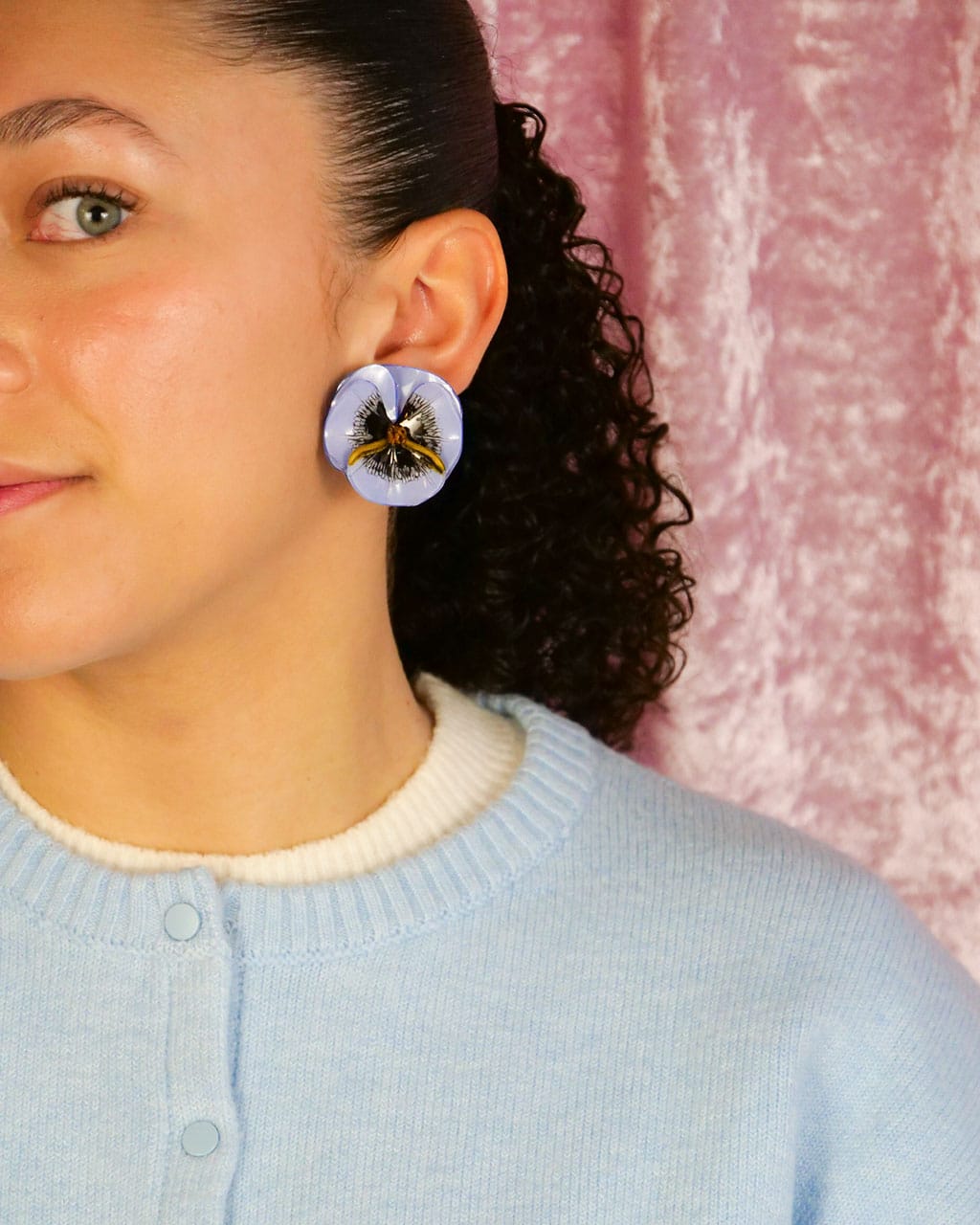 Les boucles d'oreilles colorées Pensée bleu clair portées par une jeune femme avec un pull du même bleu.
