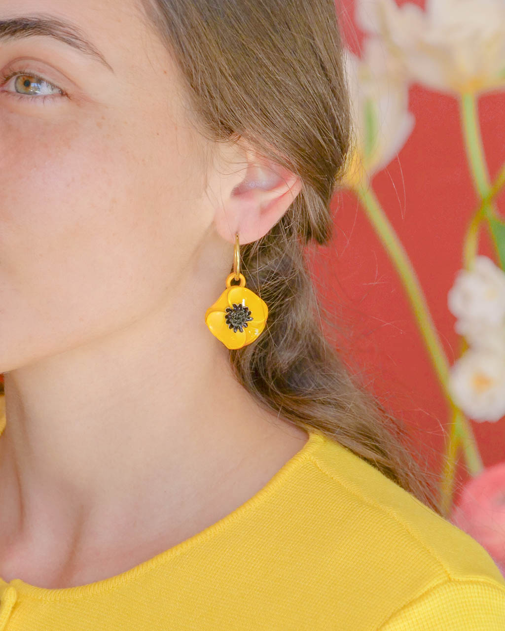 Femme portant des boucles d'oreilles créoles fleuries jaunes all-groups