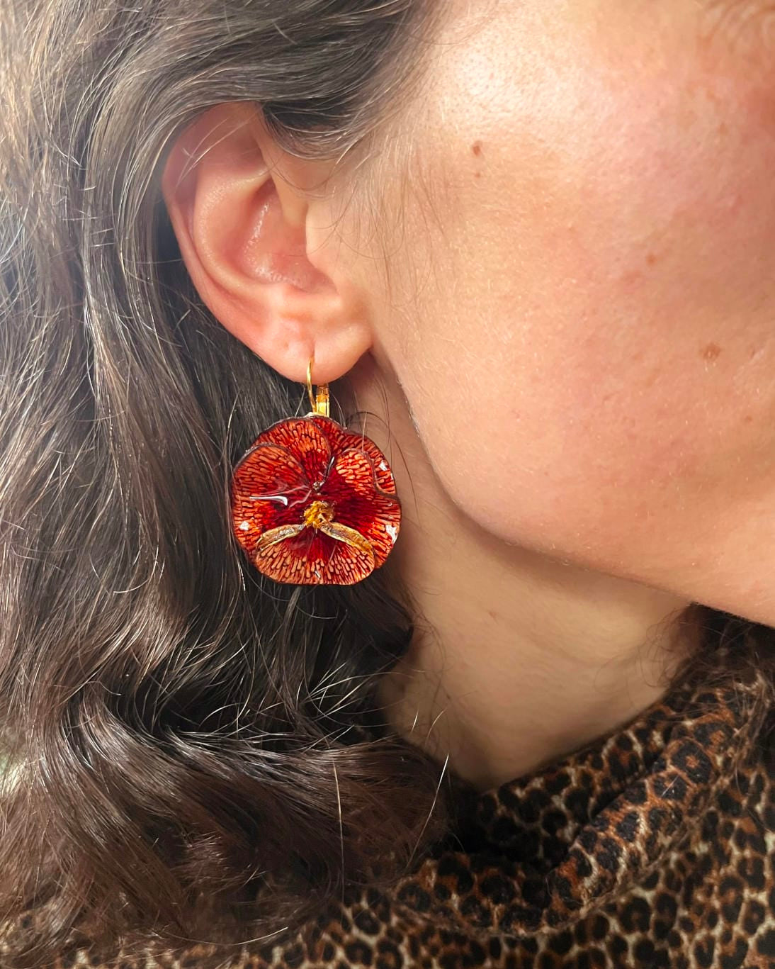 all-groups Jolies boucles d'oreilles colorées Pensée or rouge portées par une femme.