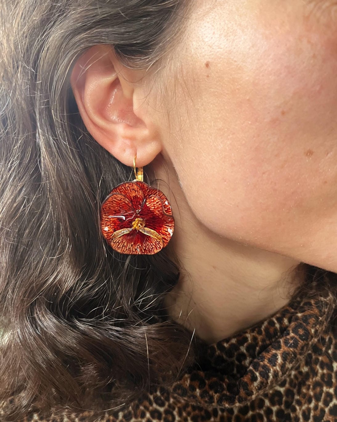 all-groups Jolies boucles d'oreilles colorées Pensée or rouge portées par une femme.