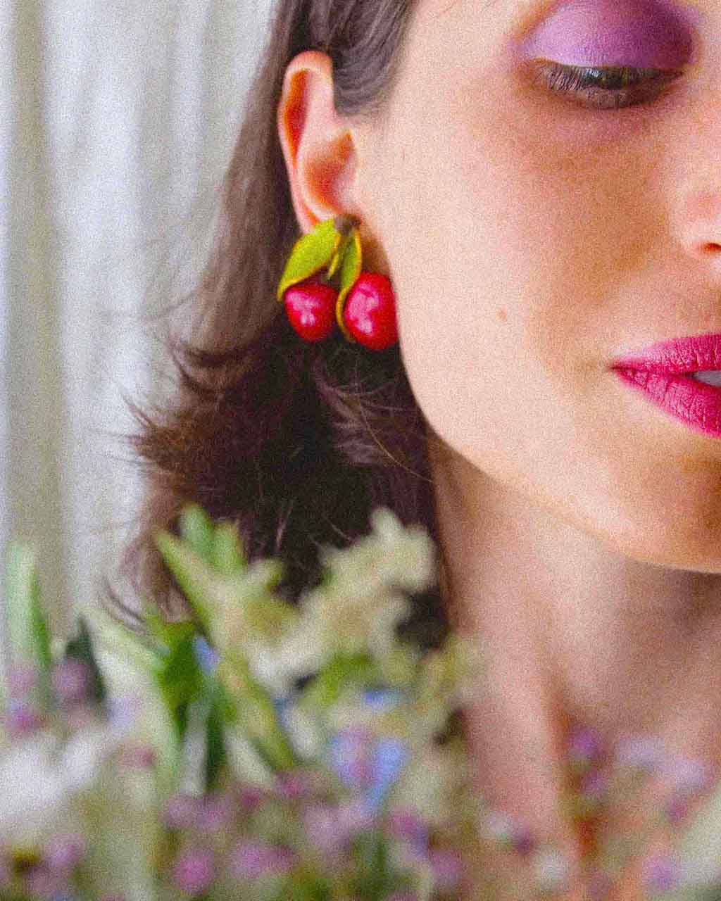 femme portant des boucles d'oreilles rouge en forme de cerise
