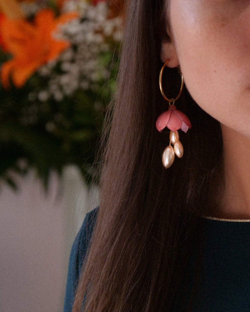 Femme portant des boucles d'oreilles créoles pendantes fleuries roses all-groups
