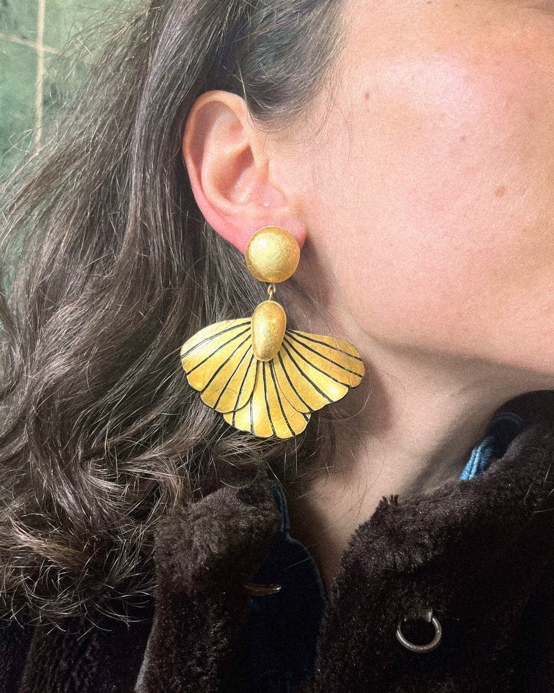 Les boucles oreilles fleurs pendantes rayées Elise portées par une femme habillant ses oreilles.