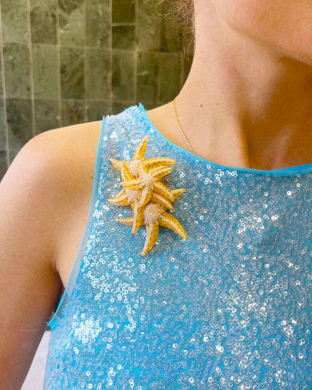 all-groups broche étoile de mer dorée sur robe bleue scintillante