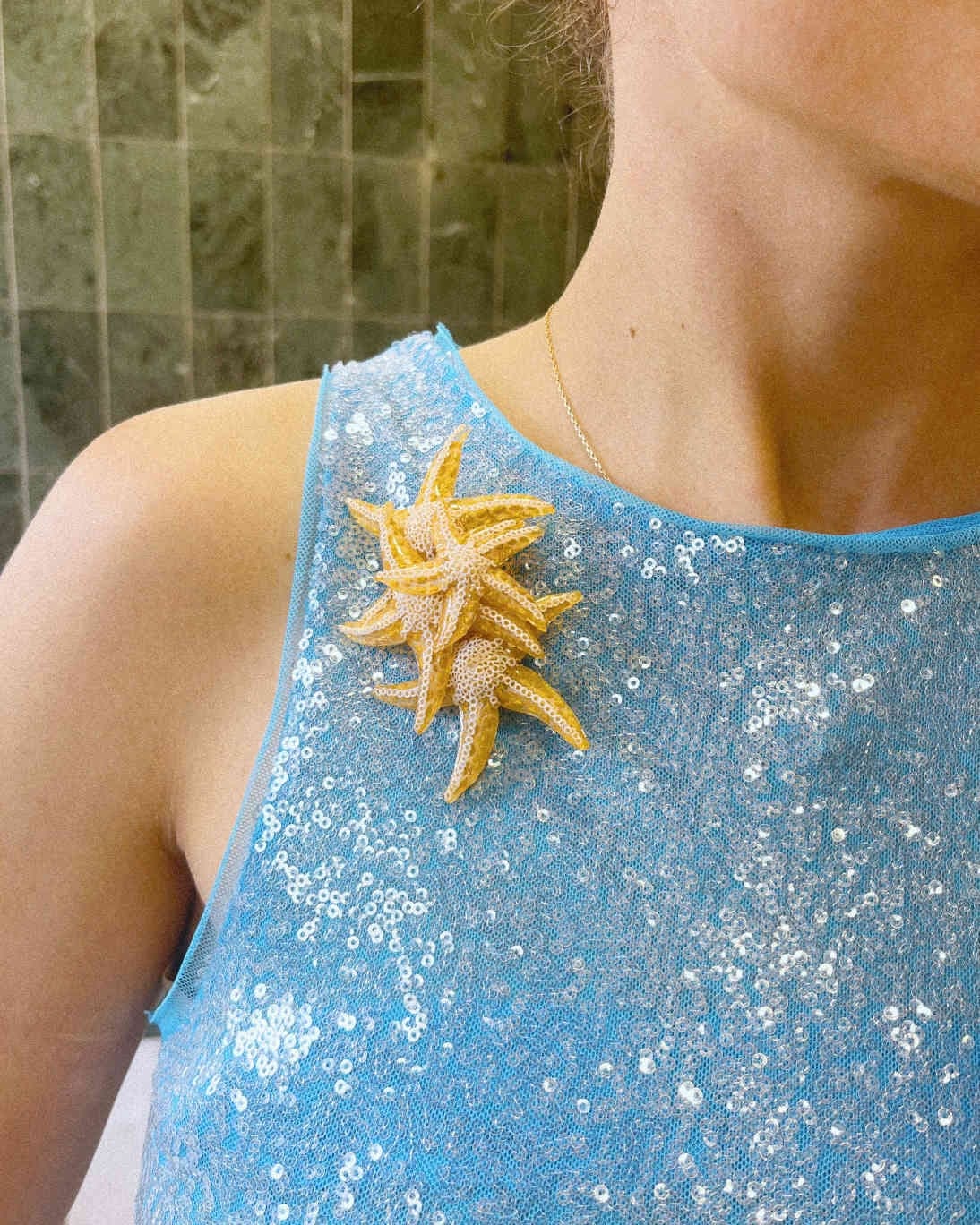 all-groups broche étoile de mer dorée sur robe bleue scintillante