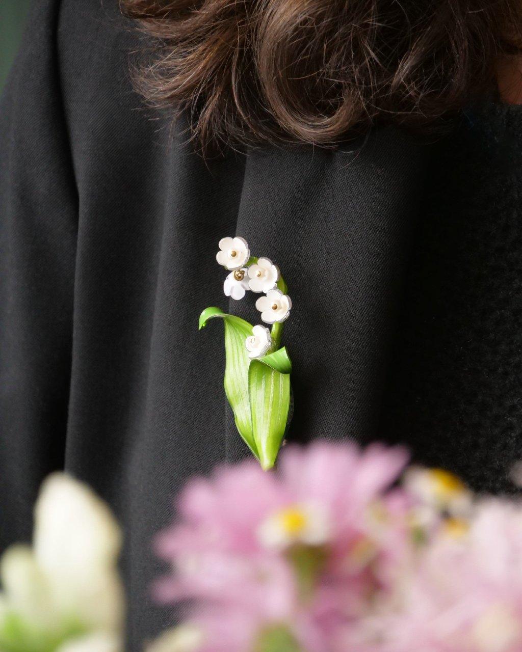 all-groups Femme portant une broche chic fleur de muguet