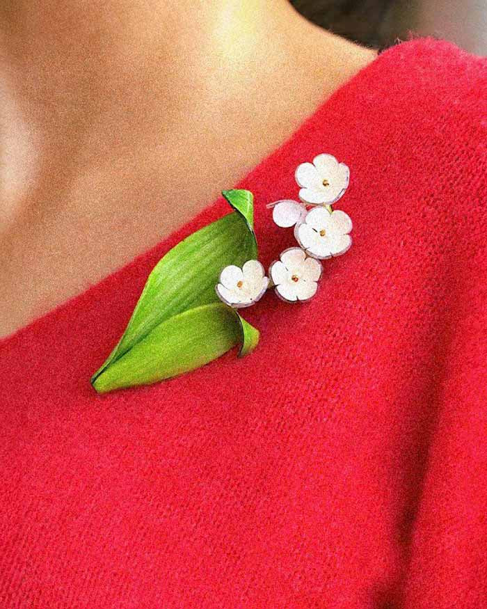 all-groups Broche chic muguet portée sur un pull rouge