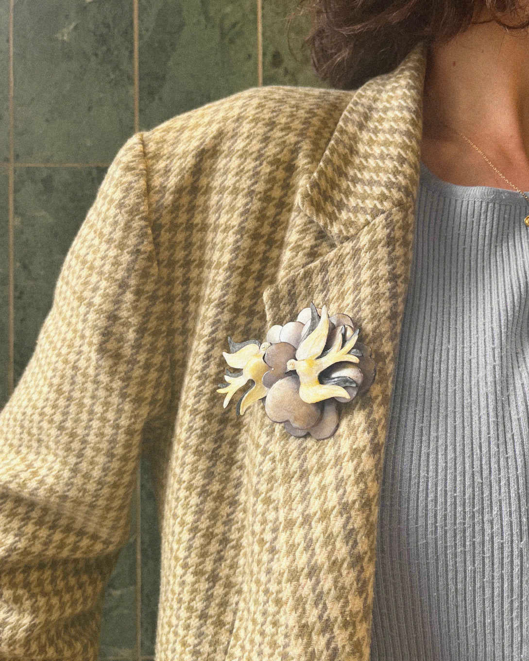 all-groups femme portant une broche oiseaux sur une veste