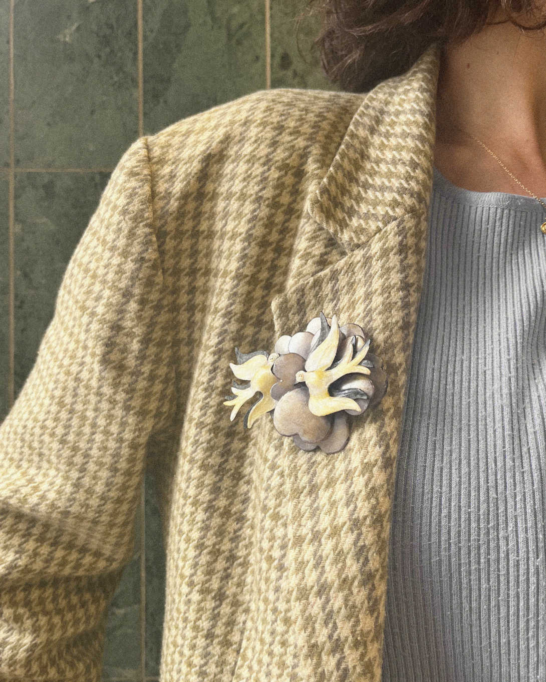 all-groups femme portant une broche oiseaux sur une veste