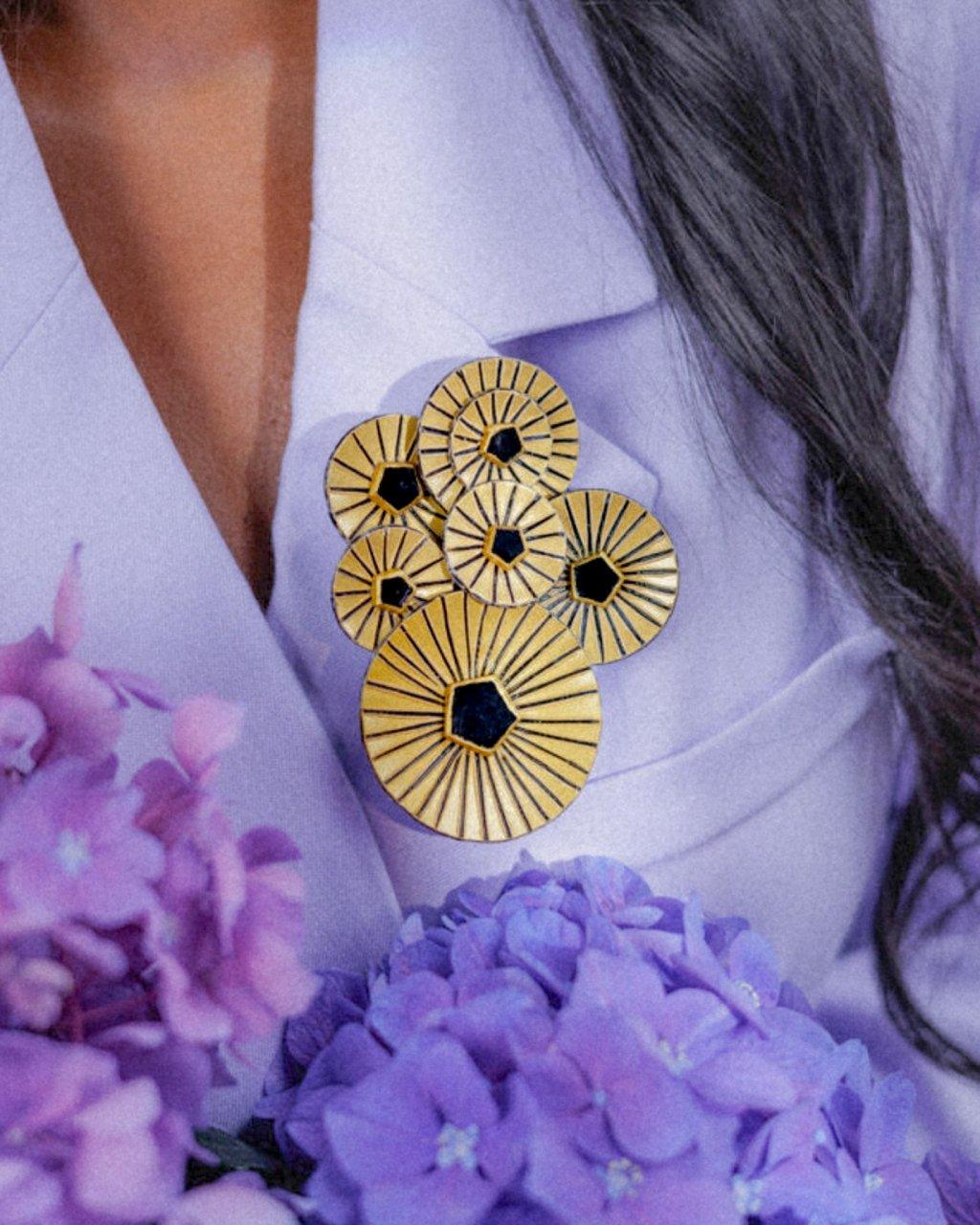 Femme portant une broche bijou graphique de couleur dorée et noire