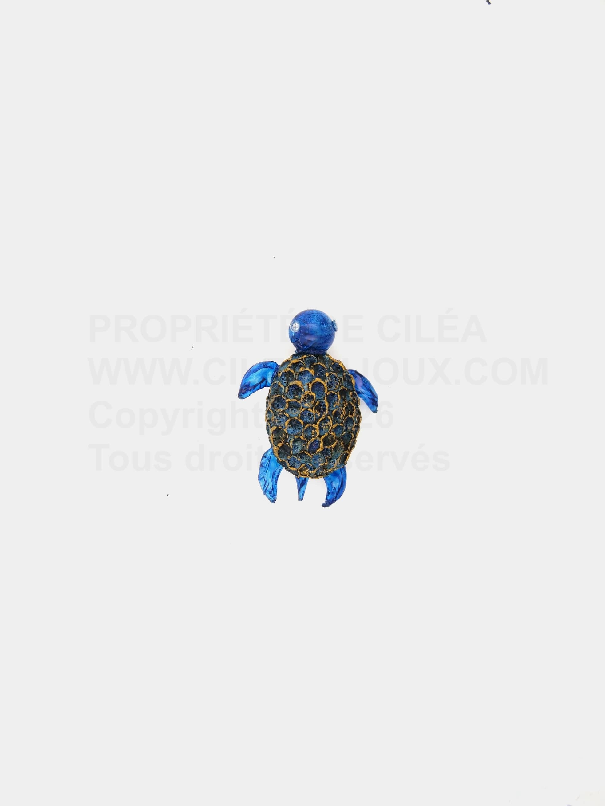 Petit broche tortue bleue avec de minutieux détails dorés sur son dos.