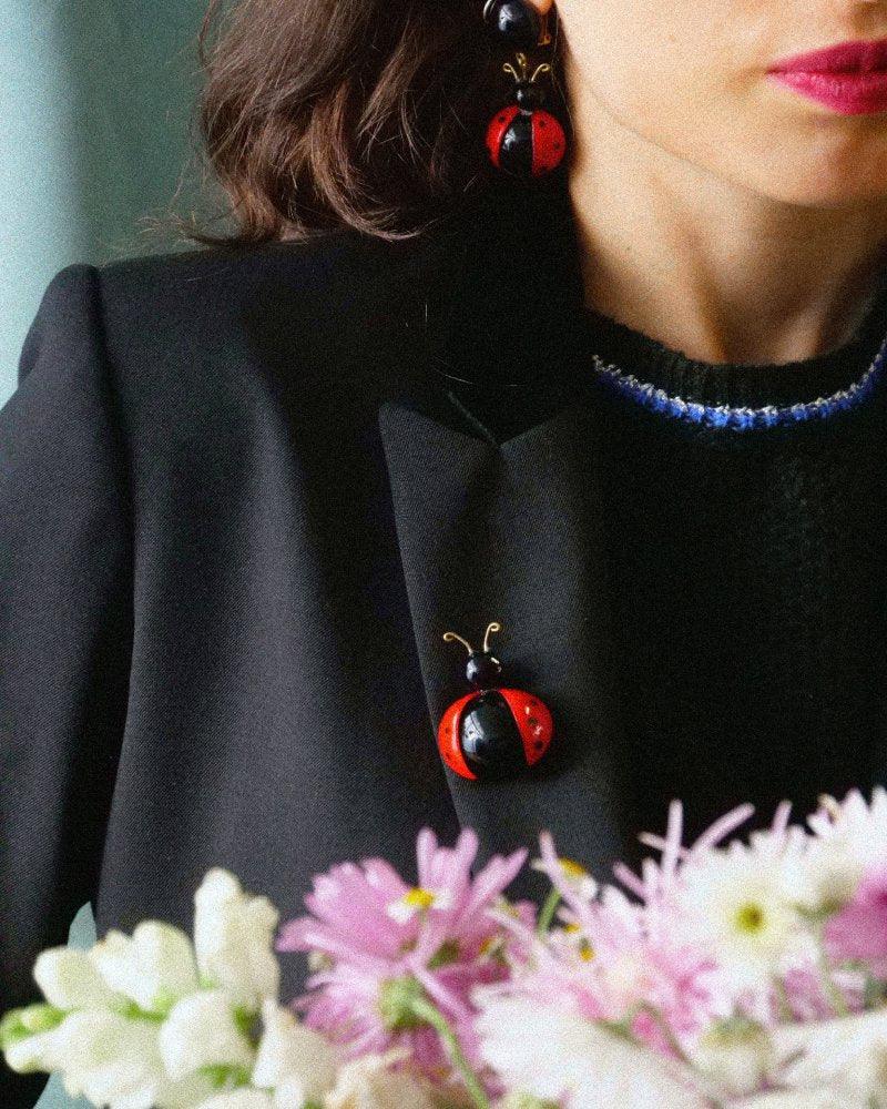 Femme portant une broche bijou fantaisie coccinelle rouge