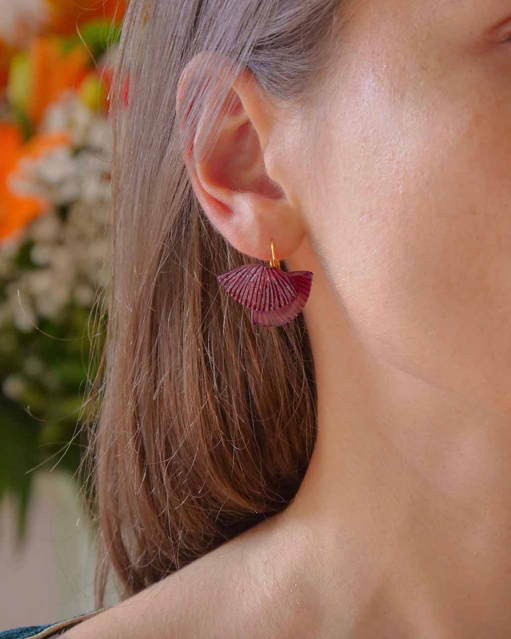 Femme portant une petite boucle d'oreille fantaisie colorée