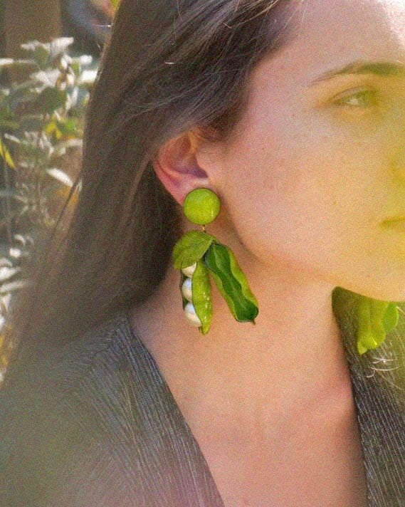 Femme portant de grandes boucles d'oreilles petits pois vertes
