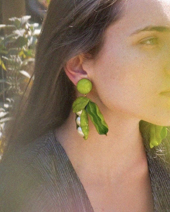 Femme portant de grandes boucles d'oreilles petits pois vertes
