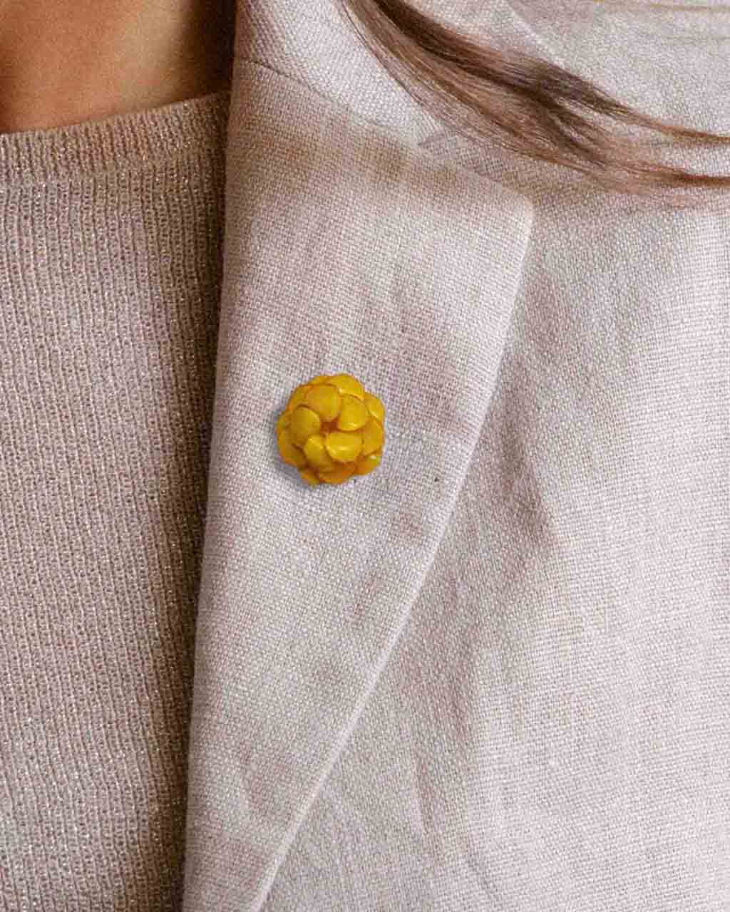 all-groups petit pin's émaillé fleuri jaune porté sur une veste