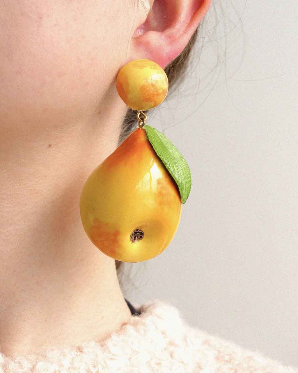 Femme portant boucle d'oreille longue en forme de fruit poire