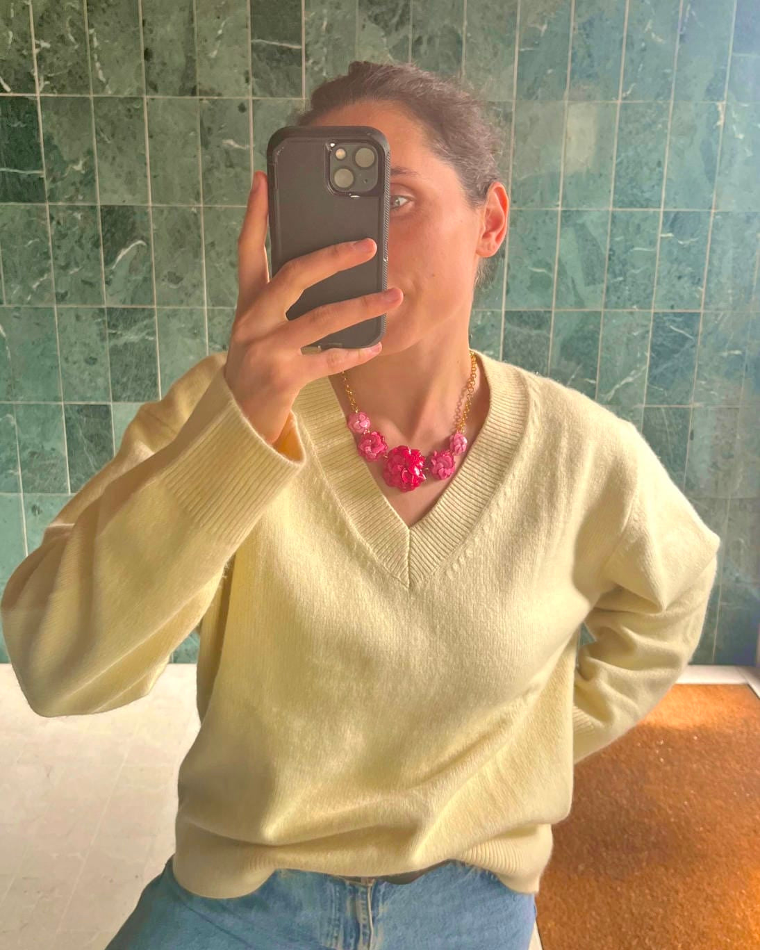 Collier fantaisie original femme rose porté par une femme qui porte un pull jaune pâle