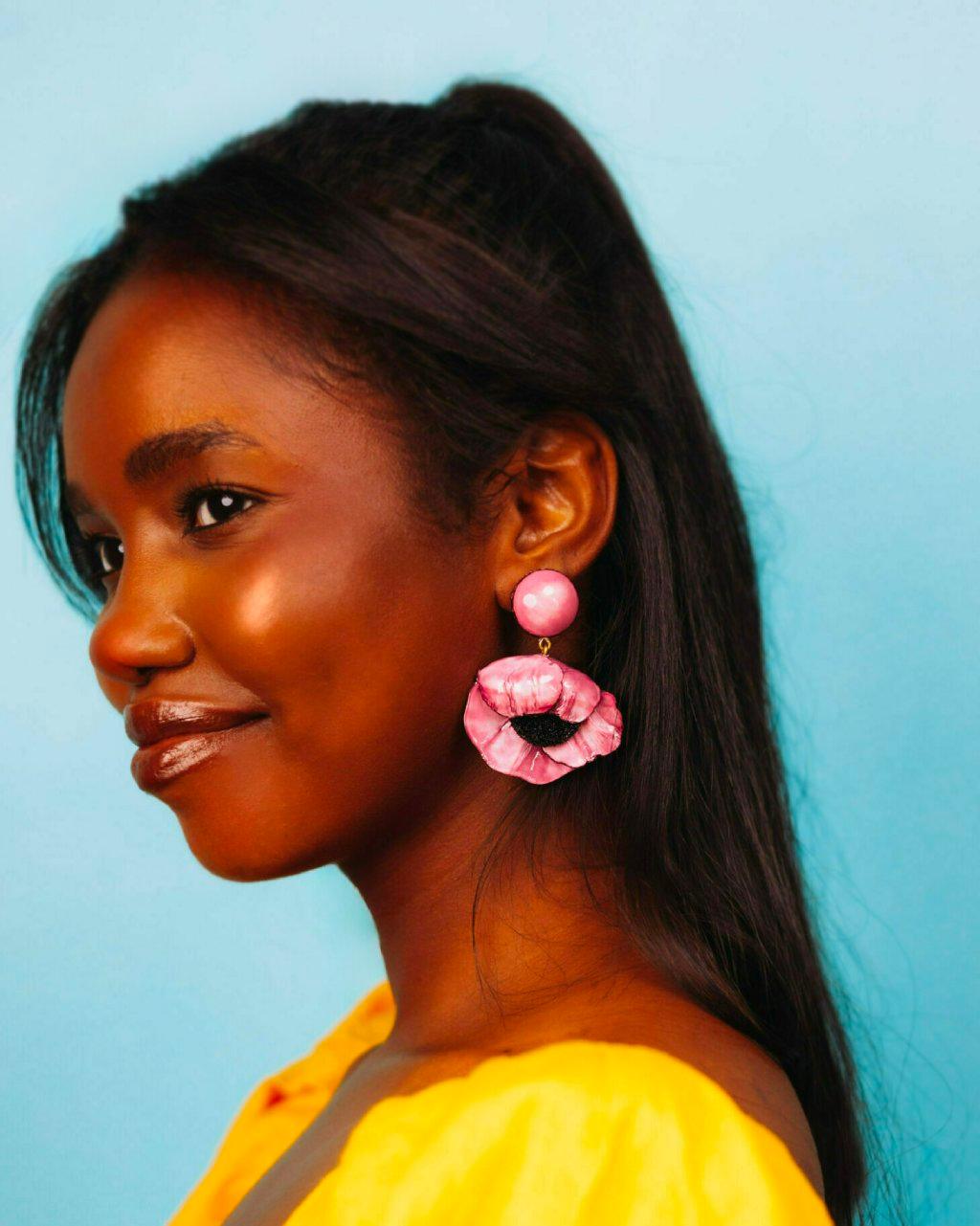 all-groups femme portant une boucle d'oreille originale fleurie de couleur rose 