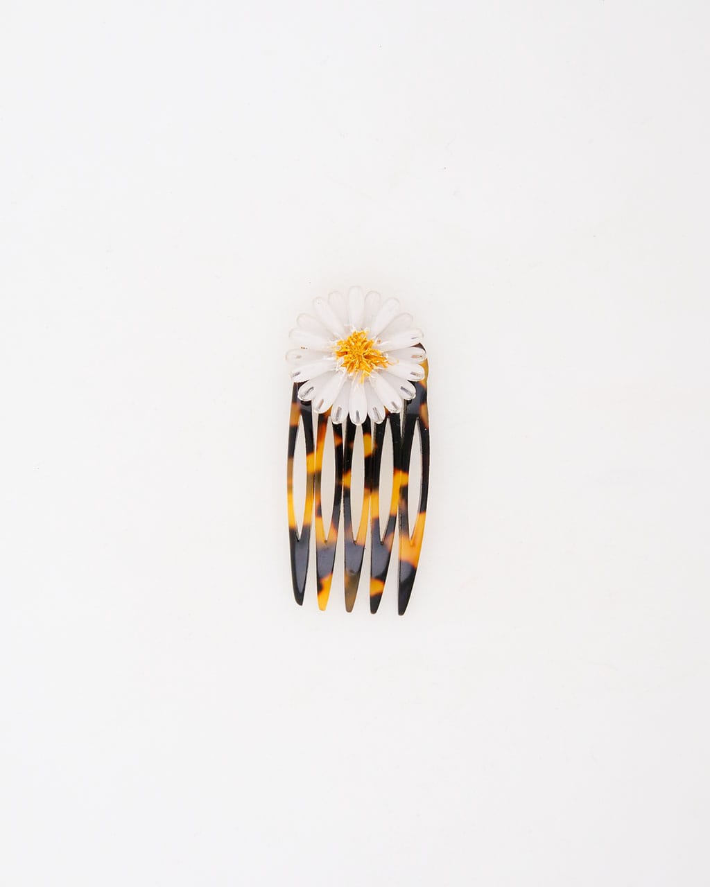 Ce petit peigne marguerite Daisy est composé d'une fleur blanche disposée sur un support de peigne en écaille.