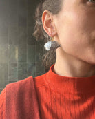 all-groups ces boucles d'oreilles originales argentées signées Ciléa Paris sont portées par une jeune femme avec un haut coloré rouge.