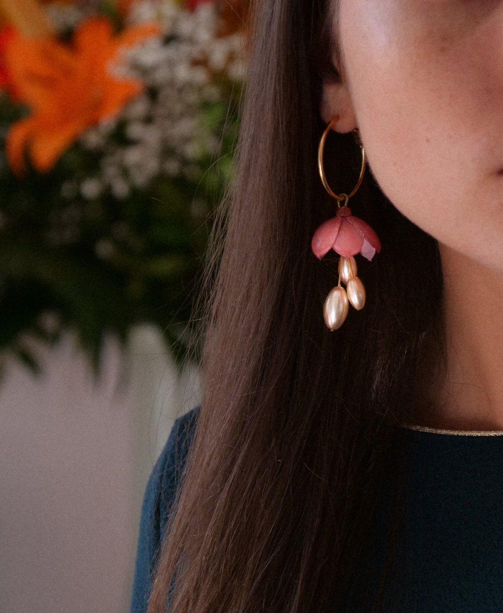 Femme portant des boucles d'oreilles créoles pendantes fleuries roses all-groups