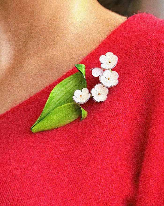 all-groups Broche chic muguet portée sur un pull rouge 