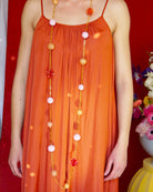 all-groups sautoir, collier long femme porté par une jeune femme avec une robe