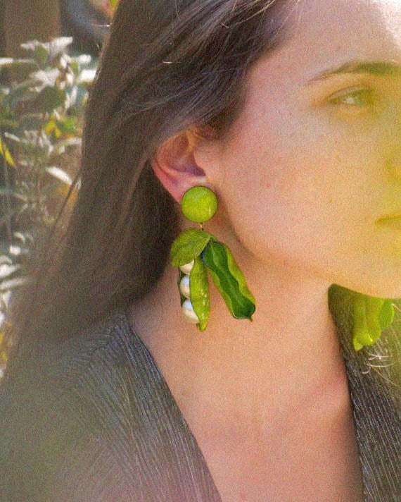 Femme portant de grandes boucles d'oreilles petits pois vertes 