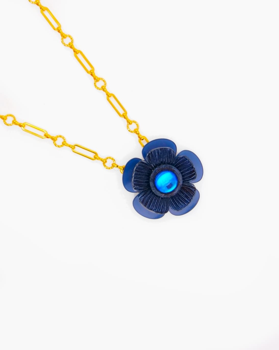 Chaque collier fleur Mona est composé d'un pendentif est de sa chaîne dorée, ici le fleur est bleue marine, nuance obtenue au coeur de l'atelier Ciléa Paris.