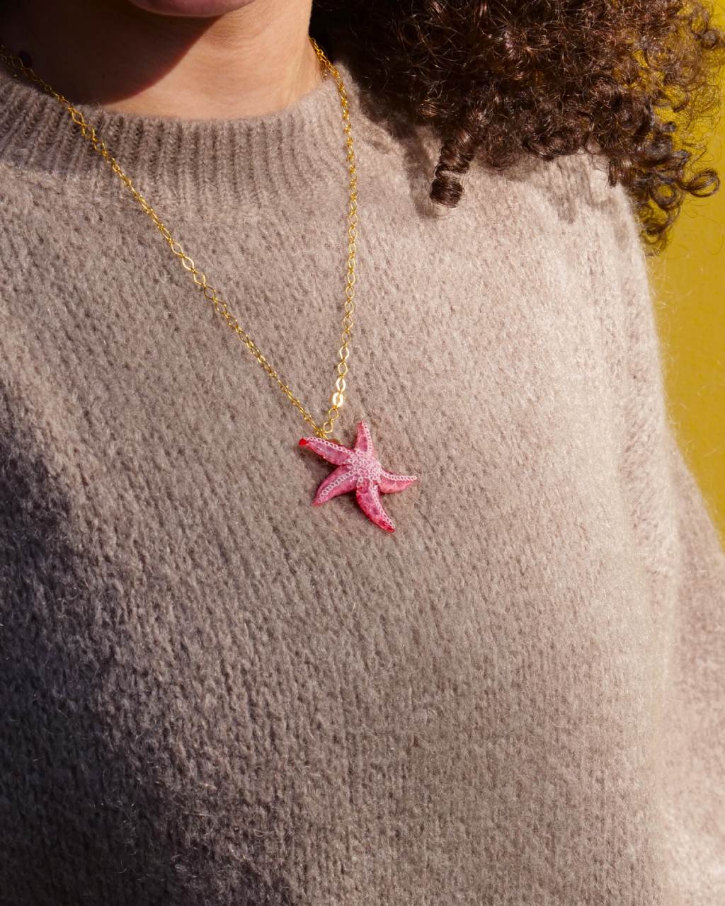 all-groups pendentif artisanal en forme d'etoile de mer Ariel, sur un pull marron clair
