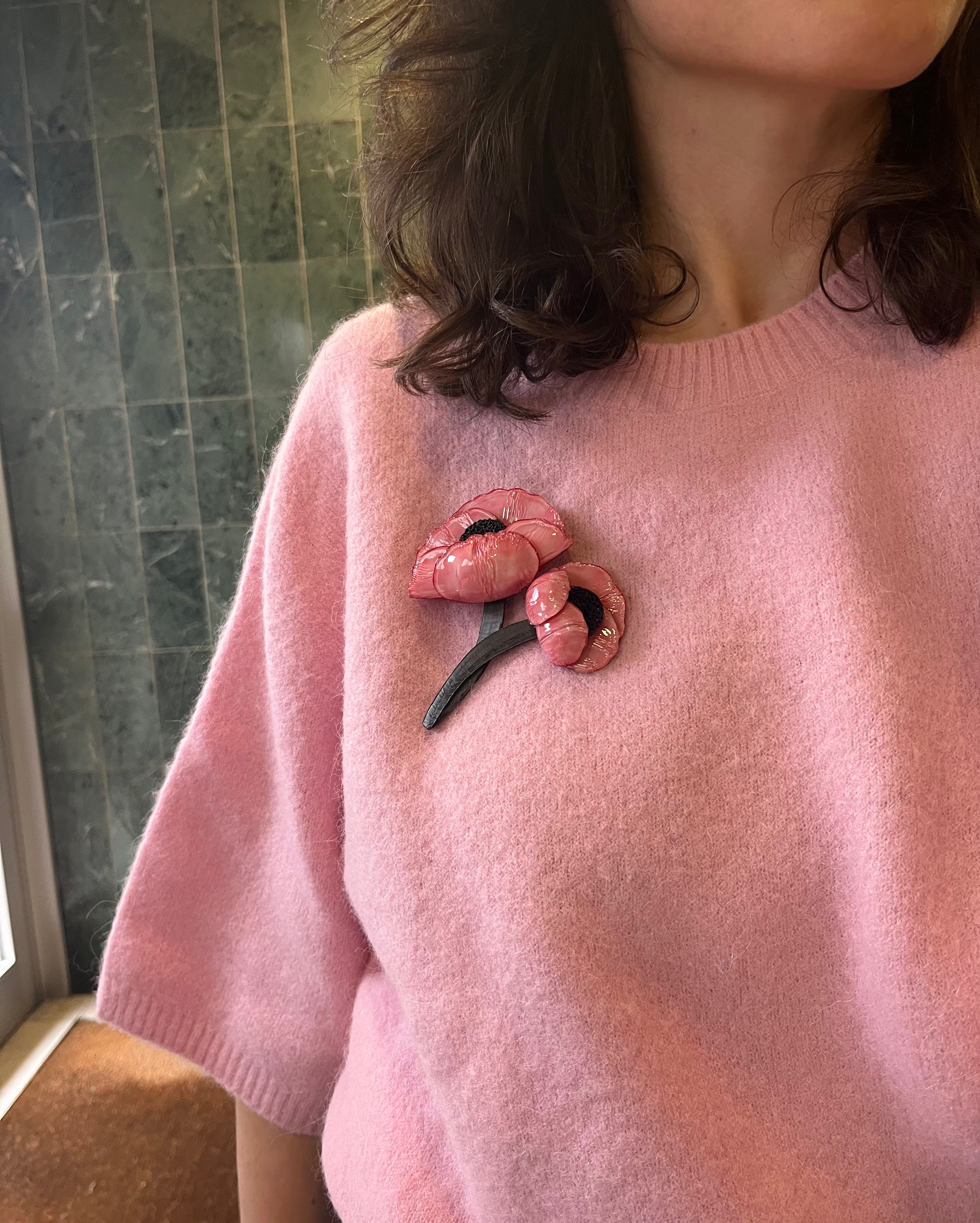 Femme portant une broche bijou rose avec son outfit all-groups